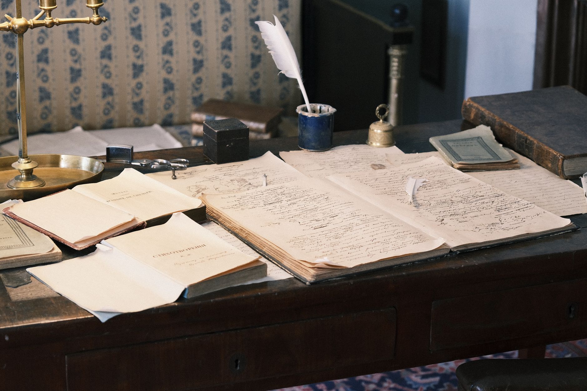 Bureau ancien couvert de manuscrits ouverts, d'un encrier avec plume blanche et d'une balance en laiton