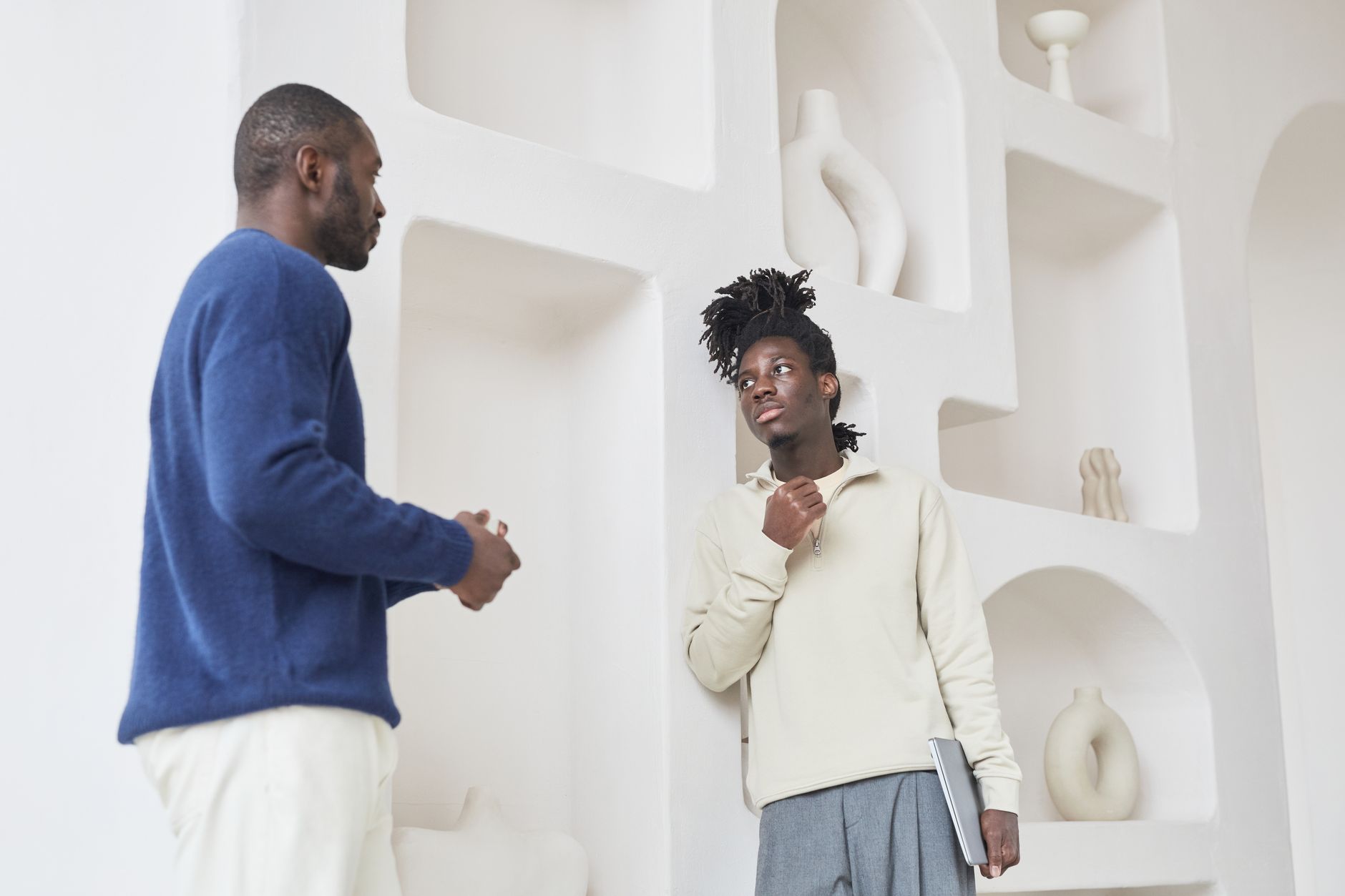 Deux hommes en conversation devant un décor intérieur moderne, discutant d'idées de manière créative.