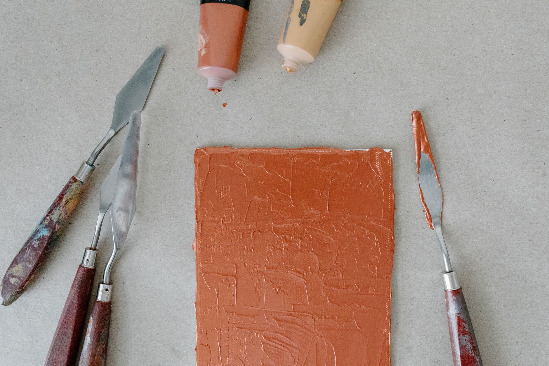 Gros plan d'une peinture texturée au couteau acrylique avec des outils artistiques sur toile.