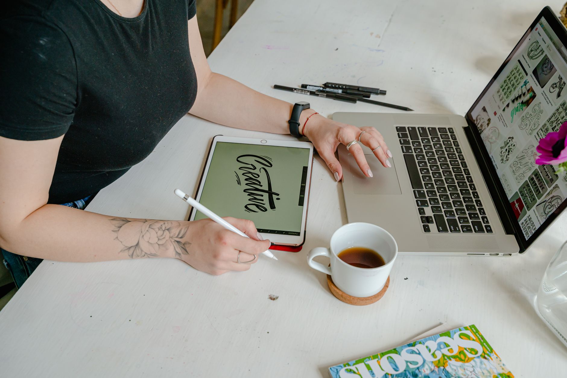 Woman working on digital design with tablet and laptop in a creative office setting.