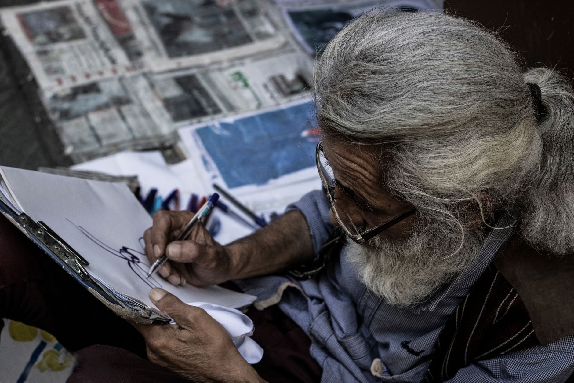 Senior artist drawing a sketch on paper, showcasing creativity and concentration.