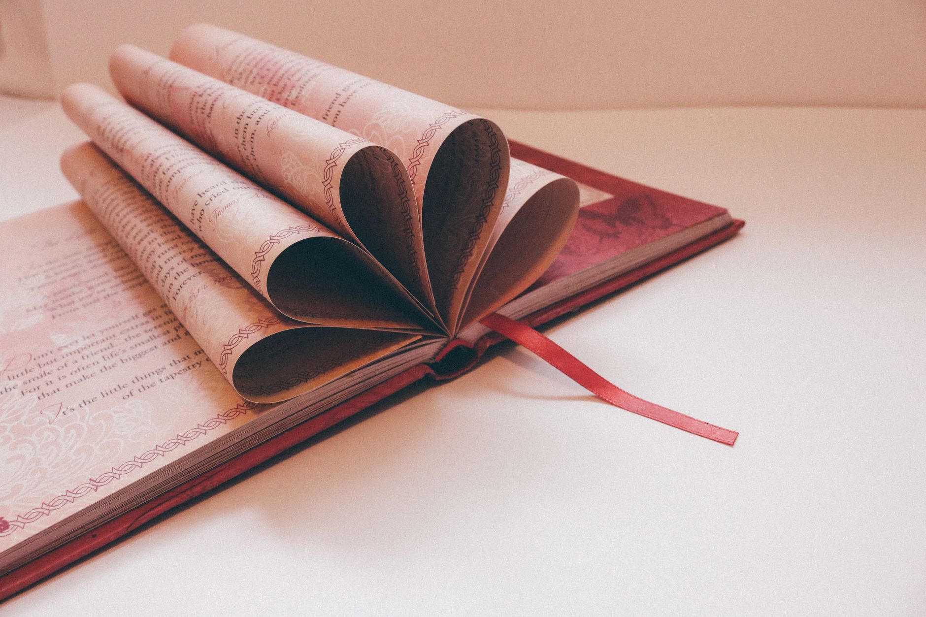 Open book with pages folded into heart shape with red bookmark. Romantic and literature theme.