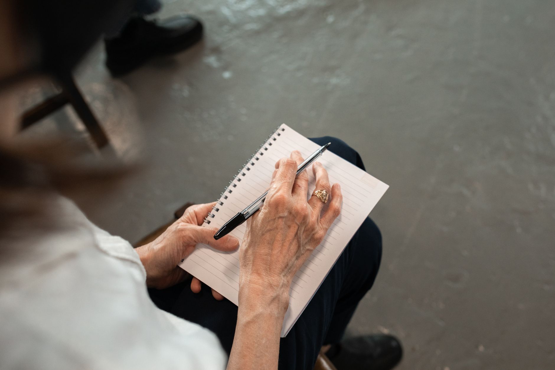 Close-up of senior hands with pen writing in a spiral notebook. Personal notes concept.