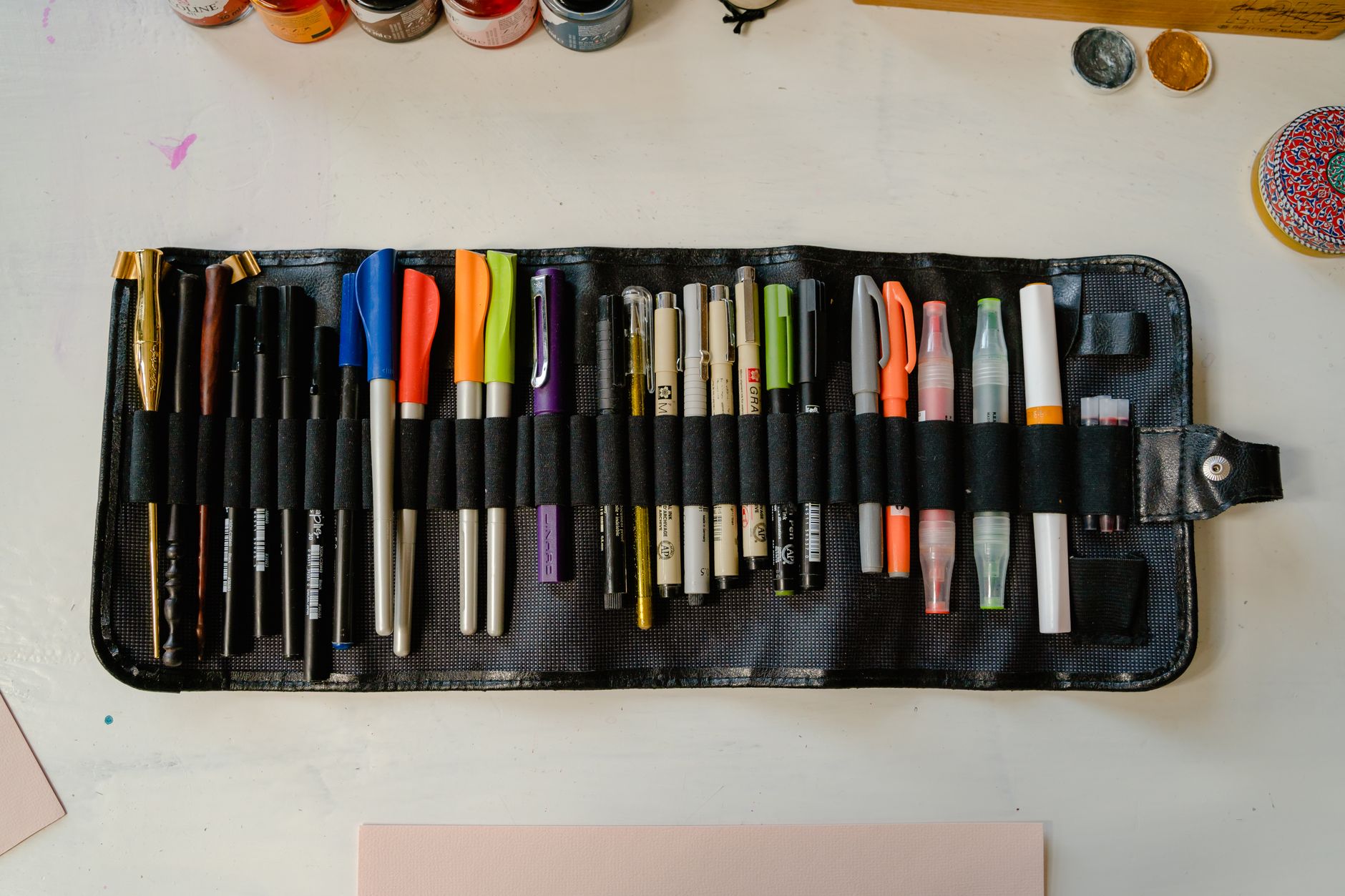 Flat lay of various art pens and supplies on a desk, perfect for creative projects.