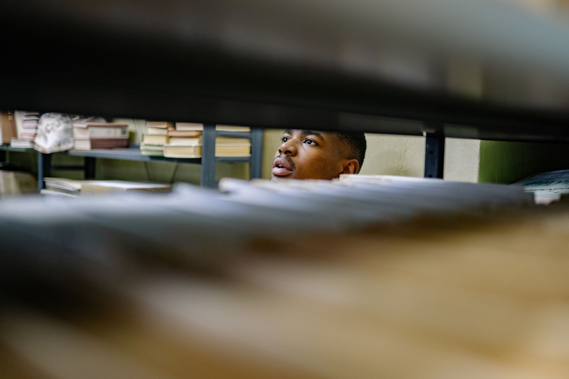 Lecteur consultant des dossiers rangés dans les rayonnages d’un fonds d’archives.